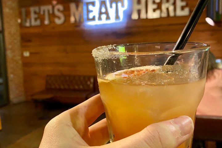 a hand holding a glass of beer on a table
