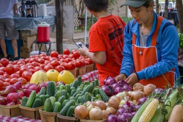 a group of people sitting at a fruit stand
